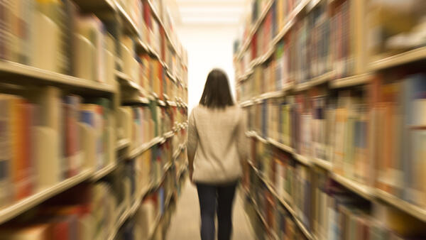 Female talking a walk in the book stacks
